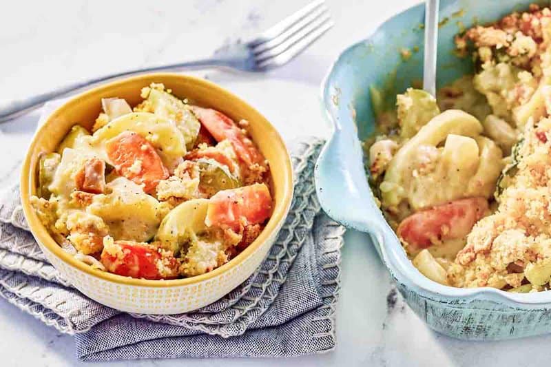 A serving of copycat Luby's squash casserole in a bowl next to the casserole.