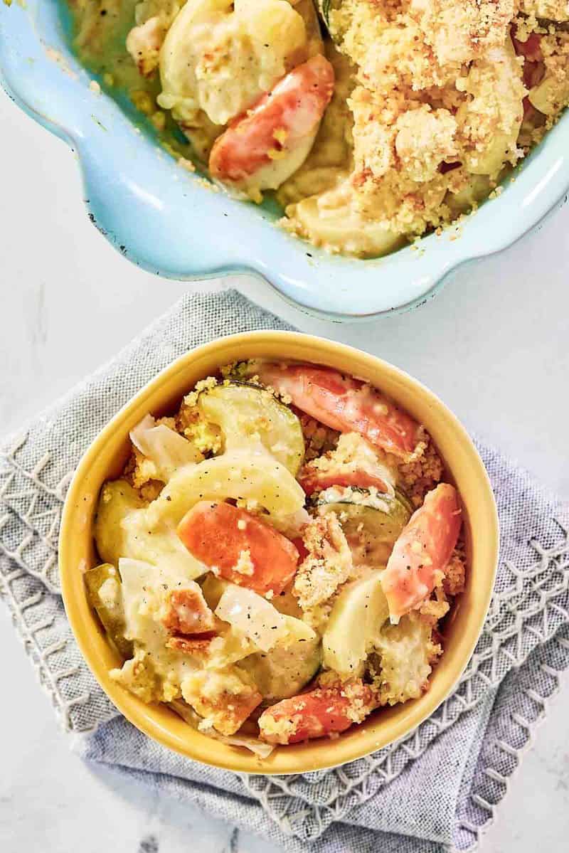 Copycat Luby's squash casserole in a baking dish and a serving in a bowl.