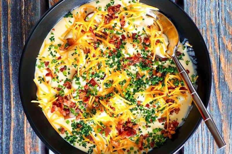 Copycat O'Charley's loaded potato soup topped with shredded cheese, bacon, and chives.