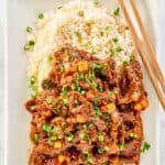 Copycat Panda Express Beijing Beef, rice, and chopsticks on a plate.