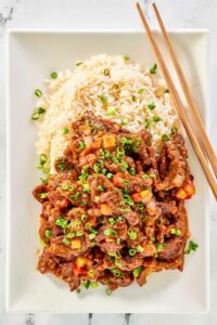Copycat Panda Express Beijing Beef, rice, and chopsticks on a plate.
