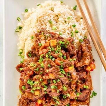Copycat Panda Express Beijing Beef, rice, and chopsticks on a plate.