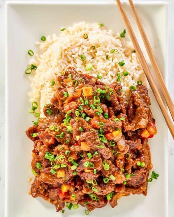 Copycat Panda Express Beijing Beef, rice, and chopsticks on a plate.
