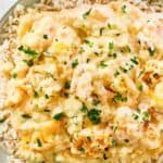 Homemade shrimp and crab au gratin on top of rice on a plate.