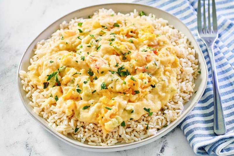 Shrimp and crab au gratin over rice on a plate and a fork next to it.