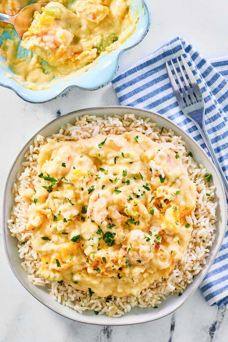 Shrimp and crab au gratin in a baking dish and over rice on a plate.