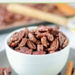A bowl of homemade spiced pecans and cinnamon sticks beside it.