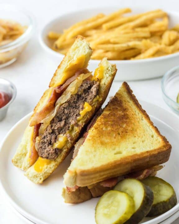 Copycat Waffle House Texas bacon patty melt on a plate and a bowl of fries.