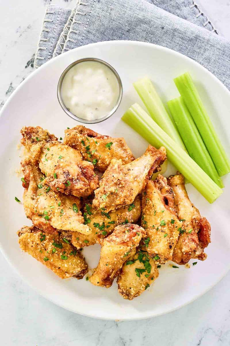 Copycat Wingstop garlic parmesan wings, cup of dipping sauce, and celery sticks.