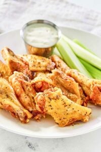 Copycat Wingstop lemon pepper wings, celery, and dipping sauce on a plate.