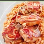 Baked pork chops and rice with onions and tomato sauce on a platter.