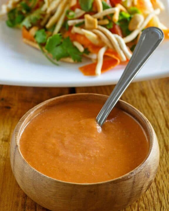 Copycat Benihana ginger salad dressing in a bowl and a salad behind it.