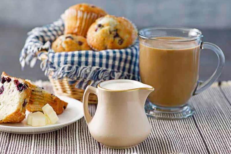 Homemade French vanilla coffee creamer, cup of coffee, and muffins.