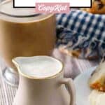 Homemade French vanilla creamer in a pitcher next to a cup of coffee.