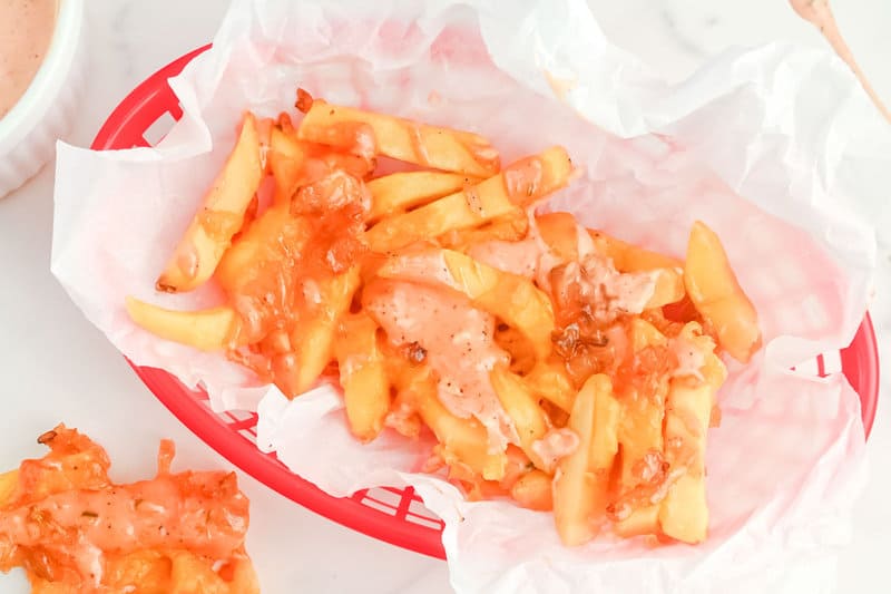Copycat In-N-Out animal style fries on parchment paper in a serving basket.