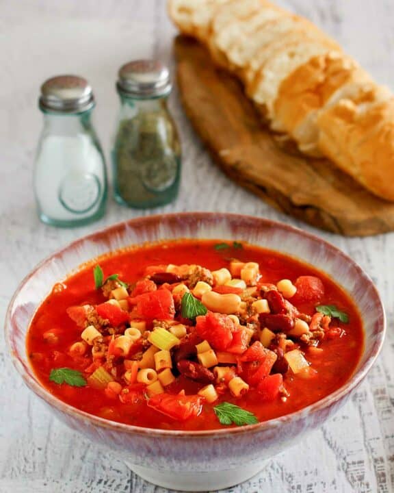 Copycat Olive Garden pasta e fagioli, bread slices, salt, and pepper.