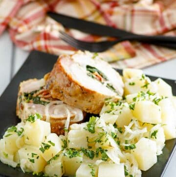 Buttery parsley potatoes and stuffed pork loin slices on a plate.