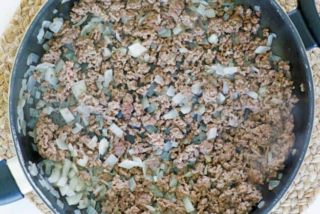 Cooked ground beef and onions in a skillet.