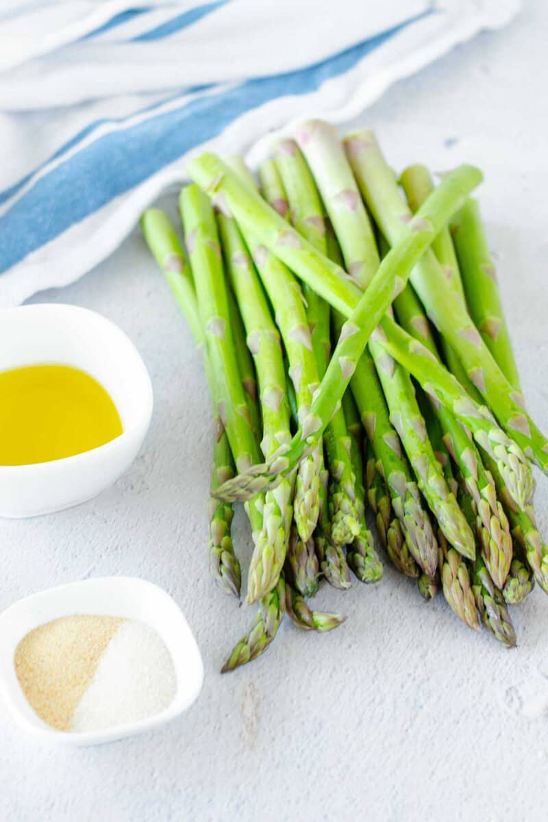 Air fryer asparagus ingredients on a marble surface.