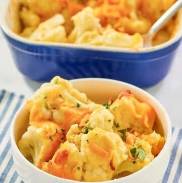 Baked cauliflower with cheese sauce serving in a bowl in front of the dish.