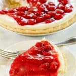 Slice of cherry cream cheese pie on a plate and the pie behind it.