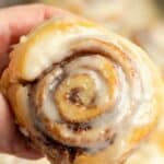 Hand holding a homemade Cinnamon cinnamon roll.