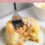Homemade Cinnabon cinnamon roll on a plate with a fork in it.
