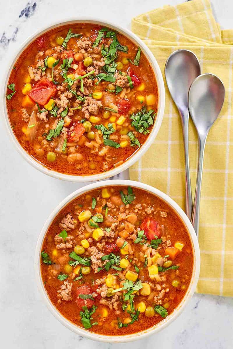 Cowboy soup in bowls and spoons next to them.