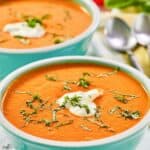 Homemade La Madeleine red pepper soup garnished with basil and cream.