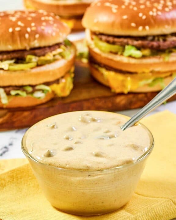 Copycat McDonald's big mac sauce in a small bowl and burgers behind it.