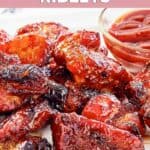 Homemade Applebee's riblets on a platter with a cup of barbecue sauce.