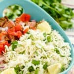 Homemade Chipotle cilantro lime rice, lime wedges, and chopped tomatoes in a bowl.