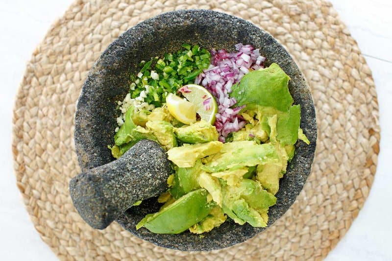Copycat Chipotle guacamole ingredients in a mortar and pestle.