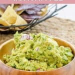 Homemade Chipotle guacamole in a bowl and tortilla chips behind it.
