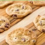 Chocolate chipper cookies spread out on a wood board.