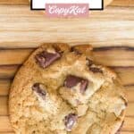 A chocolate chipper cookie on a wood board.