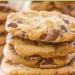 Four chocolate chipper cookies in a stack on a wood board.