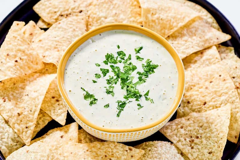 Copycat Chuy's jalapeno ranch dip in a bowl and tortilla chips around it.