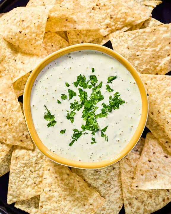 Copycat Chuy's creamy jalapeno dip and tortilla chips on a round platter.