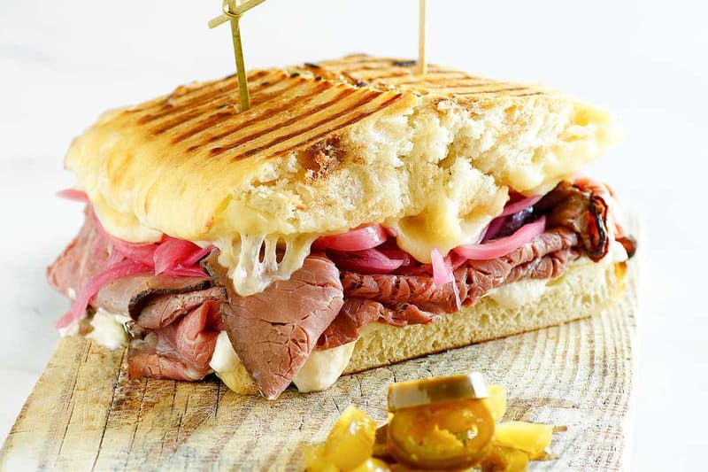 Copycat Panera steak and white cheddar panini sandwich on a wood board.