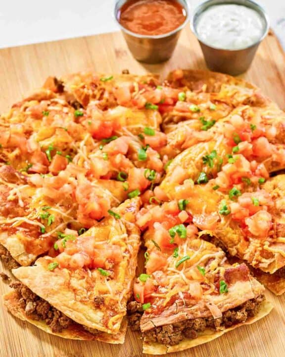 Copycat Taco Bell Mexican pizza and cups of taco sauce and sour cream.