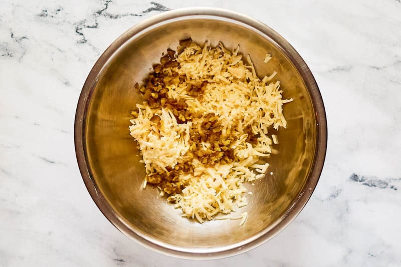 Shredded cheese and chopped jalapeno peppers in a bowl.