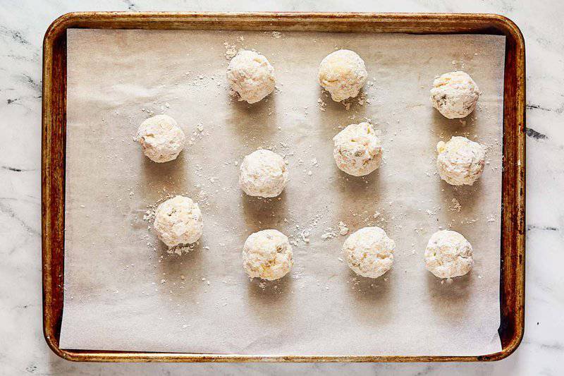 Seasoned flour coated cheese balls on a tray.