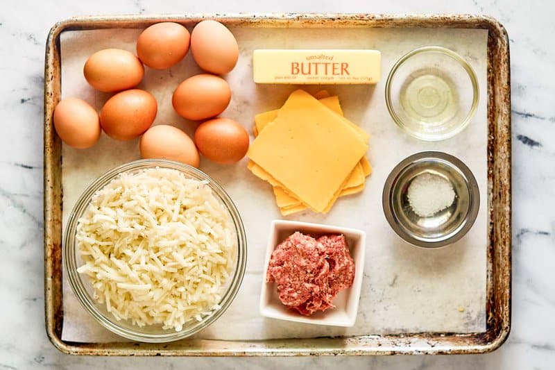 Copycat Waffle House sausage, egg, and cheese hashbrown bowl ingredients on a tray.