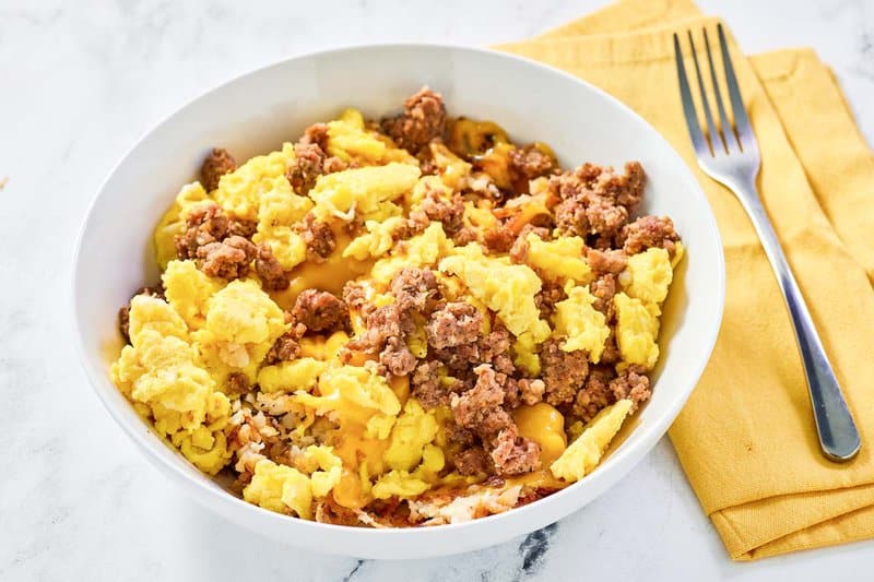 Copycat Waffle House sausage, egg, and cheese hashbrown bowl and a fork on a napkin.
