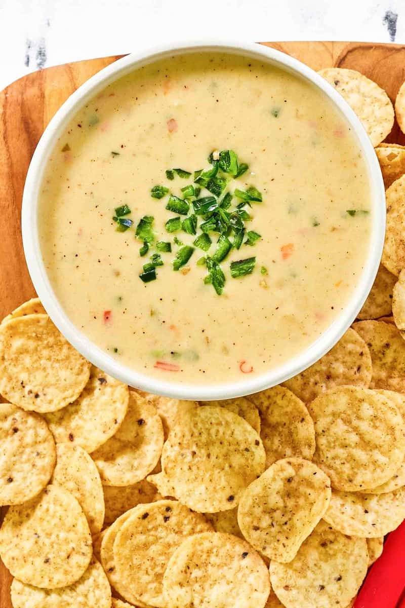 Tortilla chips and copycat Chipotle queso blanco on a wood board.