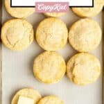 Several homemade freezer biscuits on a parchment paper-lined baking sheet.