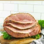 Homemade honey baked ham on a wood serving board.
