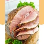 Sliced honey baked ham on a wood cutting board.