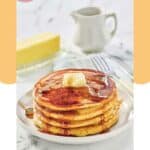 A stack of homemade IHOP protein pancakes, stick of butter, and syrup pitcher.